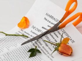 Tijeras naranjas cortando contrato de matrimonio y rosa naranja